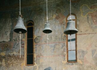 Une femme regardant avec émerveillement trois cloches suspendues dans une église ancienne.