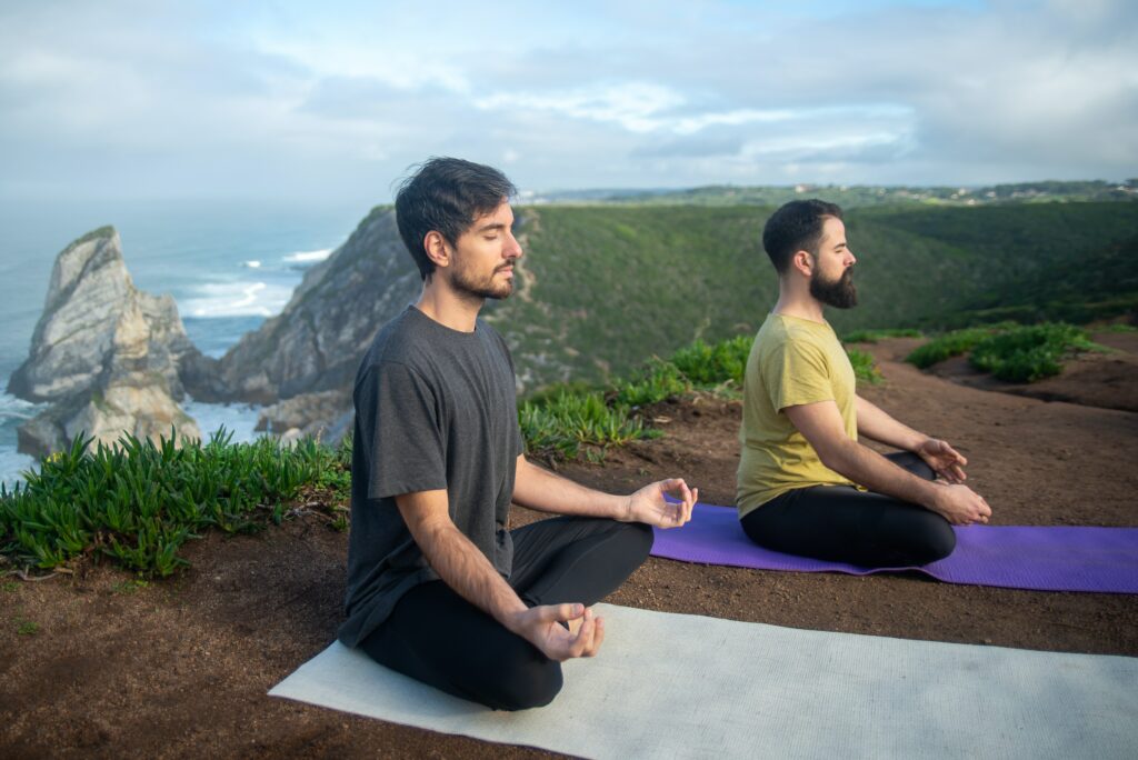 Deux hommes en plein processus de méditation lors d'une retraite spirituelle, plongés dans le calme de la nature environnante.