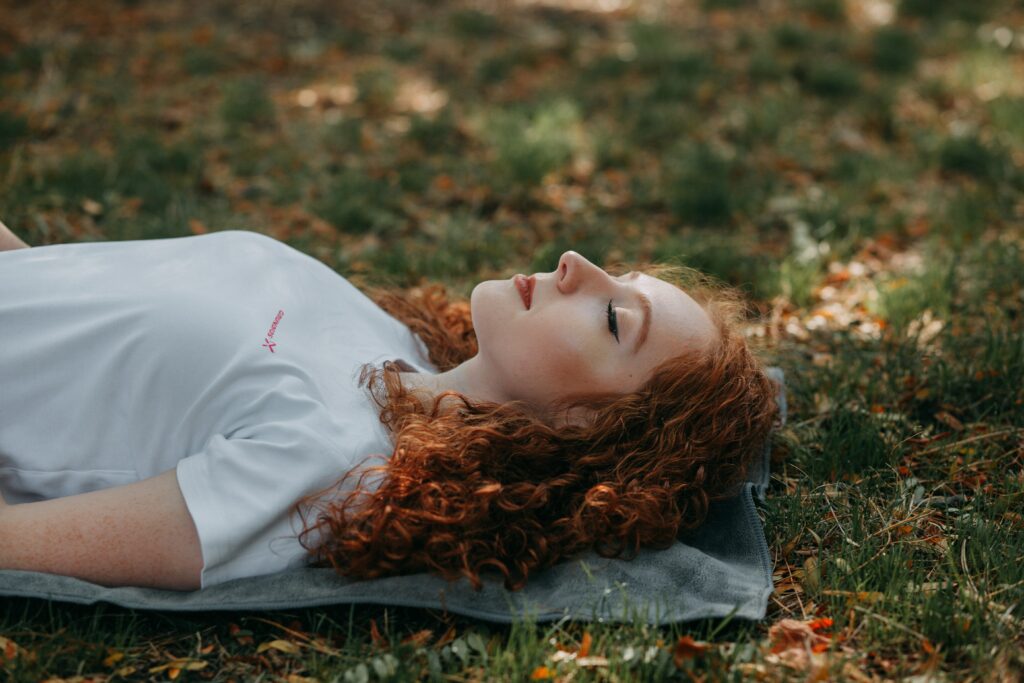 Une femme paisible reposant en pleine nature, les yeux fermés, illustrant l'influence de l'éveil spirituel sur les habitudes de sommeil