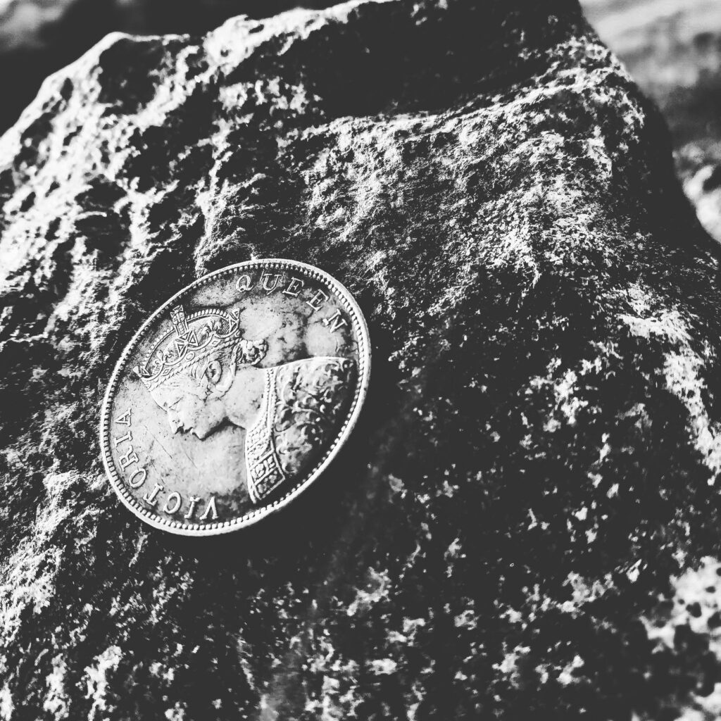 Une pièce d'argent isolée reposant sur une roche près de la plage, représentant la signification spirituelle de trouver de l'argent par terre dans un contexte naturel.