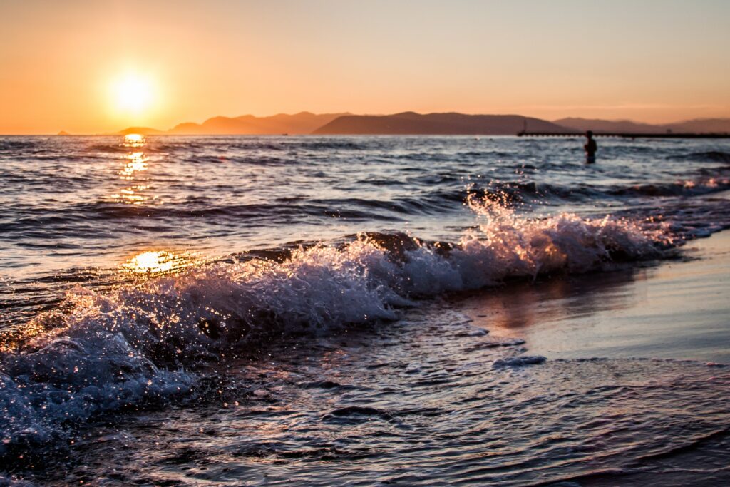 Des vagues s'écrasant sur une plage au coucher du soleil, symbolisant le changement et l'évolution, en harmonie avec le thème de la vague