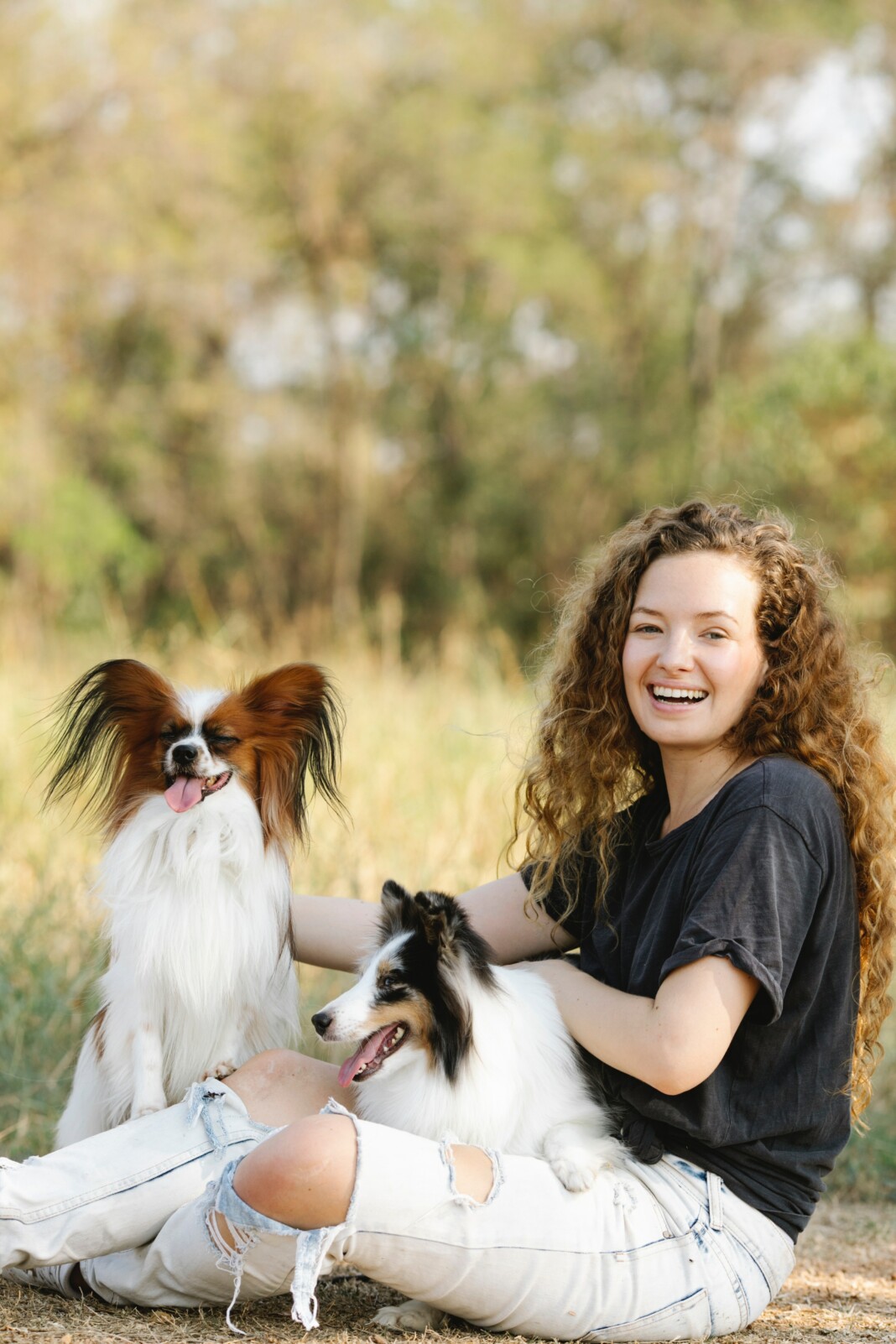 Une femme rayonnante, entourée de ses deux chiens, dégageant une aura de joie et de bonheur, illustrant la connexion profonde entre l'âme humaine et le monde animal.