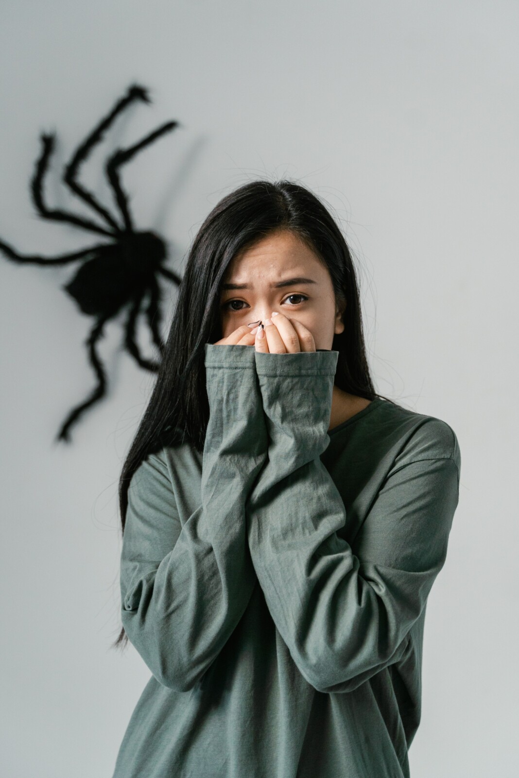 Femme effrayée regardant une grande araignée derrière elle dans une maison.