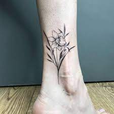Un pied orné d'un tatouage de jonquille, symbole de renaissance et de lumière.