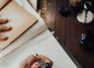 Main écrivant dans un journal spirituel avec une plume dans un bureau
